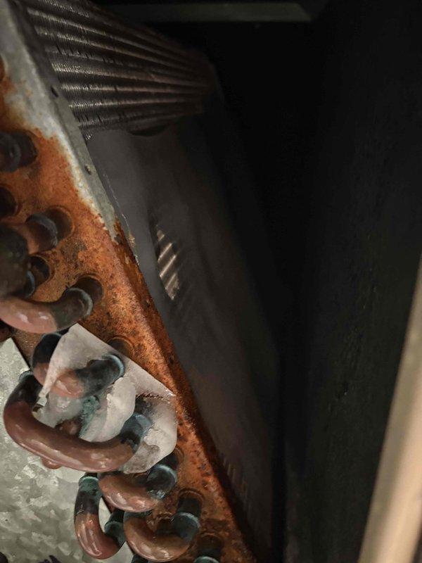 Responded to service call for Zone 2 failing to shut off when reaching temperature setpoint, with water accumulation in furnace room that worsened when thermostat was adjusted. Upon inspection of 27-year-old Bryant system, discovered severely corroded heat exchanger with extensive rust damage throughout the coil assembly and mounting components, indicating long-term moisture exposure and compromised structural integrity. Documented failed heat exchanger condition with photographic evidence showing heavy oxidation on copper tubing, deteriorated metal surfaces, and water damage consistent with heat exchanger failure causing the reported leaking issue.