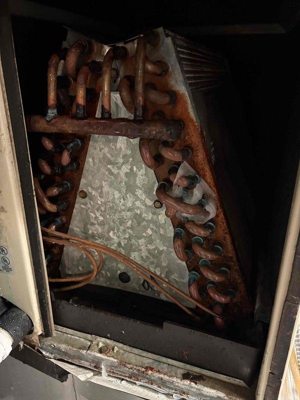 Responded to service call for Zone 2 failing to shut off when reaching temperature setpoint, with water accumulation in furnace room that worsened when thermostat was adjusted. Upon inspection of 27-year-old Bryant system, discovered severely corroded heat exchanger with extensive rust damage throughout the coil assembly and mounting components, indicating long-term moisture exposure and compromised structural integrity. Documented failed heat exchanger condition with photographic evidence showing heavy oxidation on copper tubing, deteriorated metal surfaces, and water damage consistent with heat exchanger failure causing the reported leaking issue.
