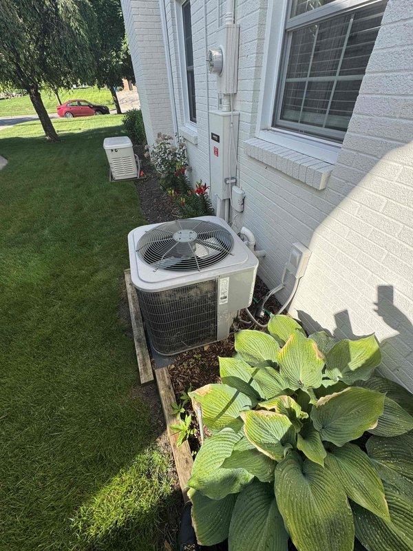 Completed comprehensive AC replacement estimate for residential property. Documented existing outdoor condenser unit mounted on wooden platform with copper refrigerant lines, exterior electrical panel, and associated utility connections. Photographed current system configuration and surrounding area to provide detailed assessment for replacement equipment sizing and installation requirements.