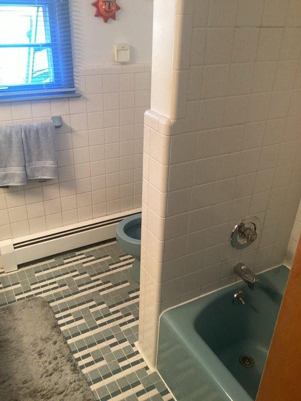 Responded to HVAC-identified water leak originating from bathtub and infiltrating basement area. Inspected vintage turquoise bathtub installation with chrome fixtures, including combination faucet, shower control, and diverter valve assembly. Documented existing conditions of tub surround with white subway tile walls and plumbing connections to assess source of water intrusion and provide recommendations for repair.