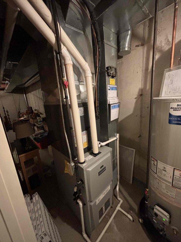 Completed same-day air conditioning system replacement including outdoor condensing unit installation on concrete pad with proper refrigerant line routing and electrical disconnect. Unit positioned against building exterior with insulated line set run through wall penetration, connecting to existing indoor furnace coil. Verified all refrigerant connections, tested electrical components, and confirmed proper system operation with adequate cooling performance.