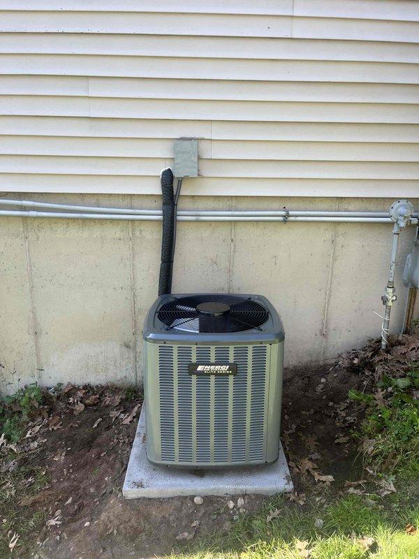 Completed same-day air conditioning system replacement including outdoor condensing unit installation on concrete pad with proper refrigerant line routing and electrical disconnect. Unit positioned against building exterior with insulated line set run through wall penetration, connecting to existing indoor furnace coil. Verified all refrigerant connections, tested electrical components, and confirmed proper system operation with adequate cooling performance.