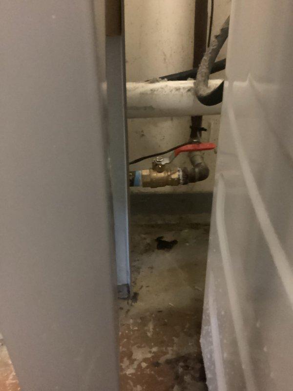 Replaced the main water shut-off valve on the house side of the plumbing system. The existing valve showed signs of failure, and the surrounding concrete floor exhibited extensive water damage and staining from previous leaks. Successfully installed new shut-off valve with red handle for easy identification and operation, ensuring proper water control to the residence.