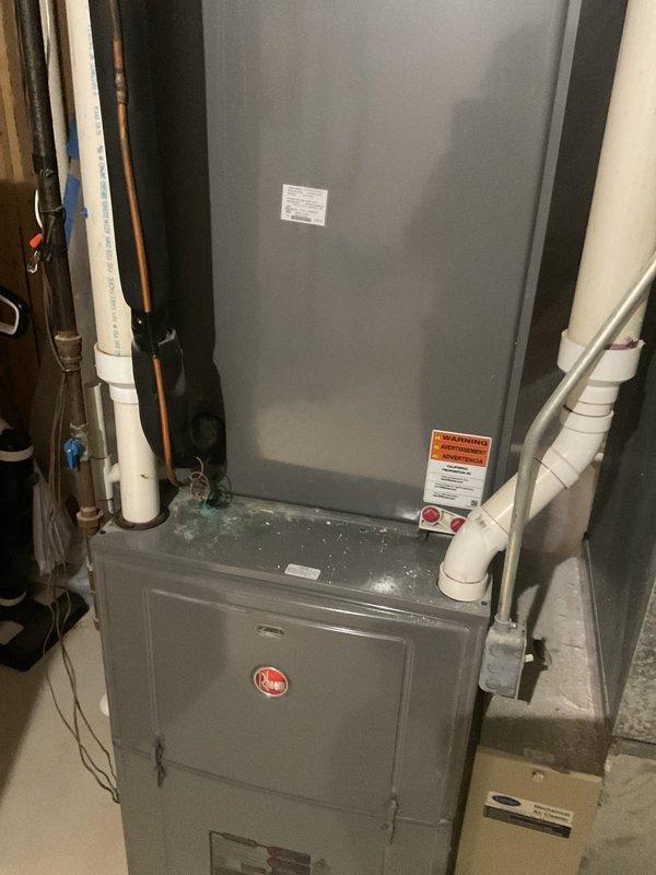 Responded to a zoned cooling system complaint where one area of the home was not receiving conditioned air while other zones operated normally. Upon inspection of the Rheem HVAC system installed in the basement, evaluated the furnace, air handler, and associated ductwork serving the affected zone. Verified refrigerant lines, electrical connections, and PVC condensate drainage system were properly installed and functioning. Documented system configuration with photos showing the vertical furnace unit with dual cabinet sections, adjacent air handler component, and connected utilities including copper refrigerant lines and condensate piping. System assessment completed to identify zone-specific cooling failure while confirming main equipment operational status.
