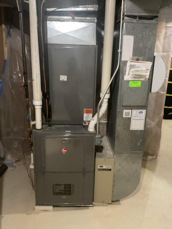 Responded to a zoned cooling system complaint where one area of the home was not receiving conditioned air while other zones operated normally. Upon inspection of the Rheem HVAC system installed in the basement, evaluated the furnace, air handler, and associated ductwork serving the affected zone. Verified refrigerant lines, electrical connections, and PVC condensate drainage system were properly installed and functioning. Documented system configuration with photos showing the vertical furnace unit with dual cabinet sections, adjacent air handler component, and connected utilities including copper refrigerant lines and condensate piping. System assessment completed to identify zone-specific cooling failure while confirming main equipment operational status.