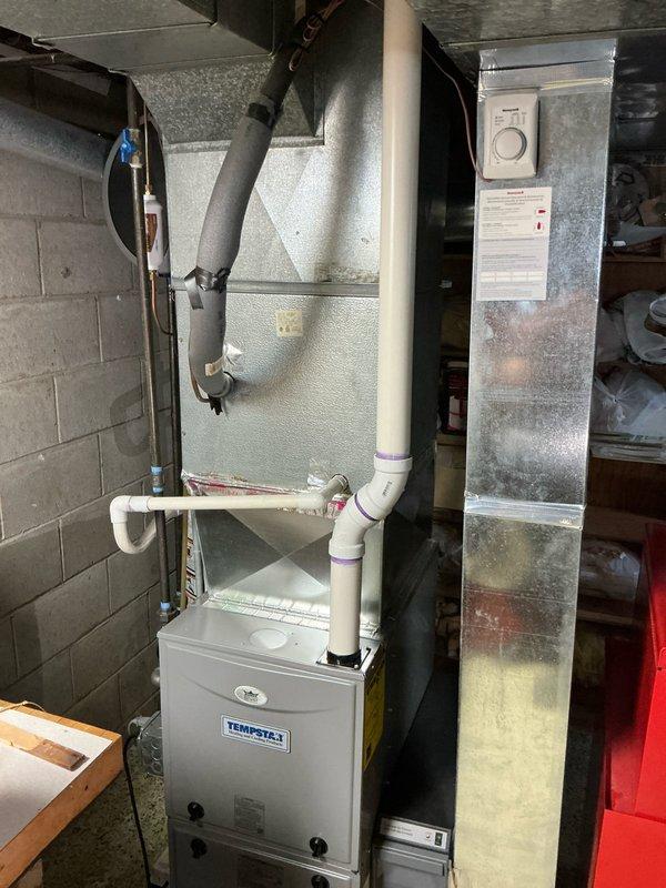 Performed estimate for non-operational air conditioning system at residential property. Inspected outdoor condenser unit with black grille body and beige top cover, along with associated refrigerant lines and wall penetrations. Evaluated basement HVAC equipment including Tempstar furnace, metal plenum cabinet, and ductwork connections. Documented existing system conditions with photos to provide replacement options for homeowner decision-making process.