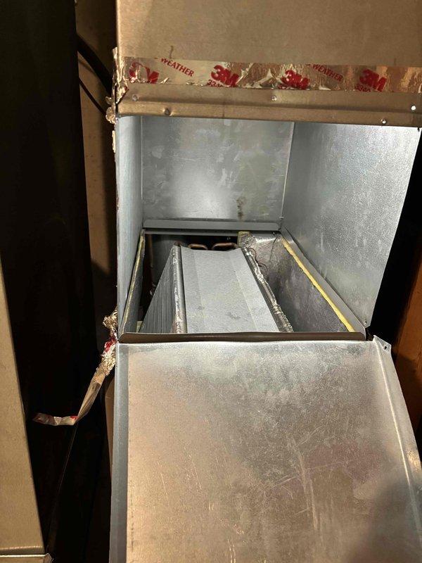 Responded to air conditioning leak complaint on 5-year-old York system. Upon inspection, accessed air handler unit and identified water leakage issue. Inspected internal components including air filter housing, evaporator coil area, and condensate drainage system. Documented equipment condition showing normal operational wear with dust accumulation on metal panels and interior components. Verified proper sealing around insulation and ductwork connections. Photographed findings for service records.