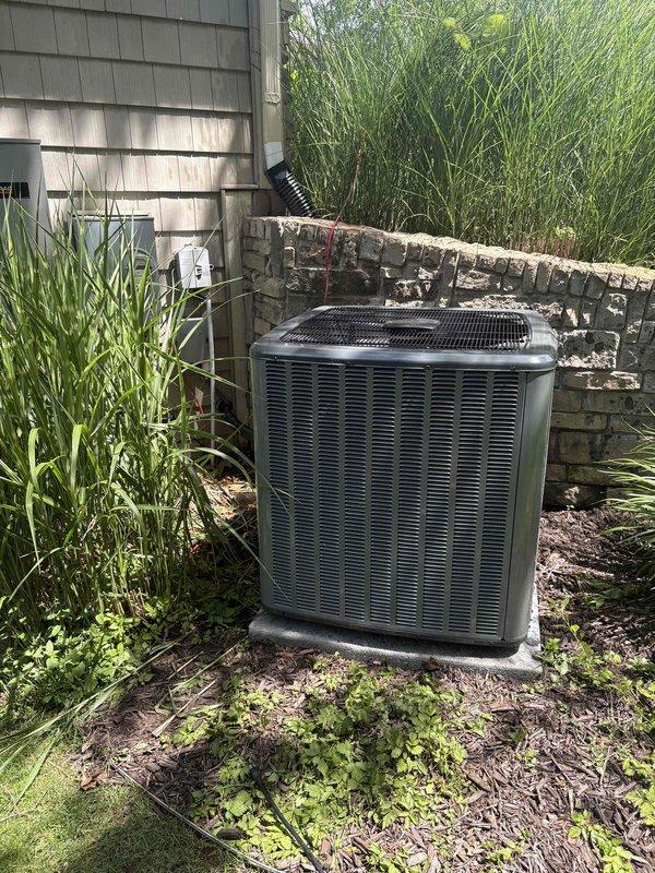 Completed full HVAC system replacement including indoor furnace unit and outdoor condenser. Installed new furnace in utility closet with proper venting using white PVC intake and exhaust pipes, connected refrigerant lines with insulation, and mounted wall control. Positioned new outdoor condenser unit against stone wall with proper clearance, ran electrical conduit, and verified system startup and operational parameters within manufacturer specifications.