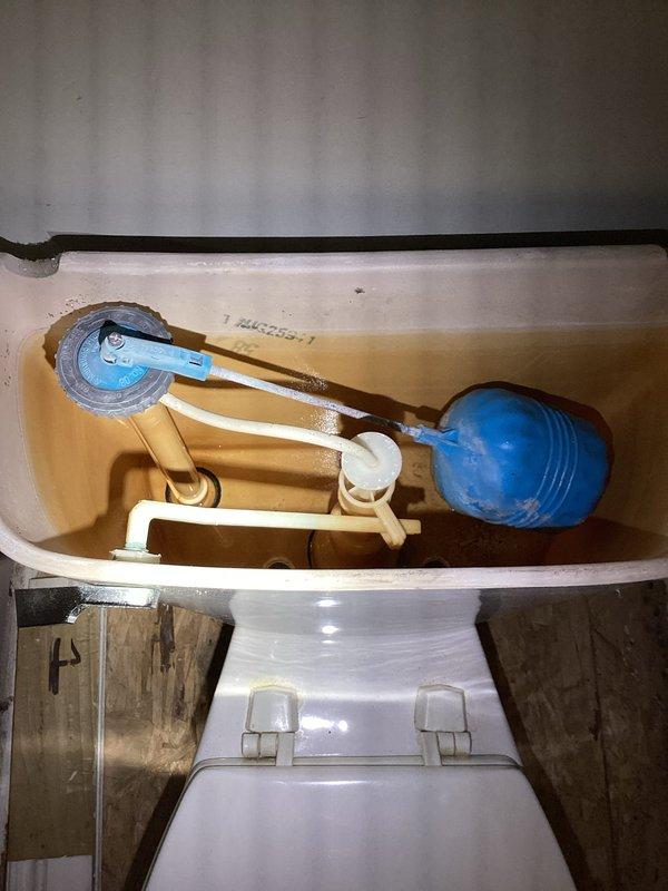 Responded to emergency call for overflowed toilet that caused approximately one inch of water accumulation in basement. Upon arrival, water supply had already been shut off by customer. Performed diagnostic inspection of toilet tank components and flush mechanism to determine cause of overflow for insurance documentation purposes. Inspected fill valve assembly, float mechanism with blue rubber ball float, and flush lever operation. Examined tank interior revealing water staining and mineral deposits indicating age-related wear. Conducted thorough inspection of toilet base mounting and wax ring seal area, identifying potential failure points in plumbing connections. Documented all findings with photographs showing internal tank components, fill valve condition, float assembly operation, and floor flange installation. Provided detailed assessment of toilet system condition and probable causes of overflow incident to support insurance claim determination.