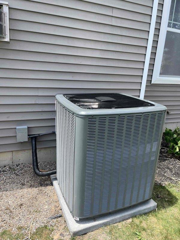 Completed full residential air conditioning system replacement including outdoor condenser unit and indoor furnace/air handler. Removed existing HVAC equipment and installed new condenser on existing concrete pad with proper gravel base. Unit positioned against exterior wall with refrigerant lines and electrical conduit run through wall penetration. Indoor air handler installed in basement mechanical room with PVC condensate drain piping and proper ductwork connections to existing black flexible supply trunk. Verified all refrigerant line connections, tested electrical connections at both indoor and outdoor units, and confirmed proper system operation. All equipment secured according to manufacturer specifications with appropriate clearances for service access and airflow.
