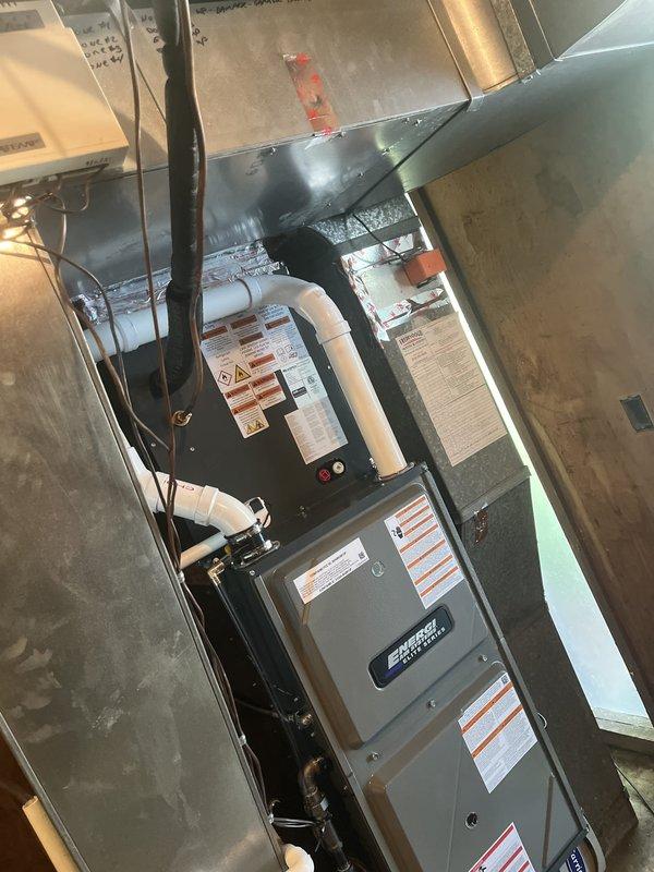Completed full HVAC system installation in basement utility space. Installed new high-efficiency furnace with proper venting using white PVC piping, connected all necessary ductwork including metallic supply plenum and distribution branches, and established electrical connections with appropriate safety disconnect. System was tested for proper operation, airflow verified, and all manufacturer safety labels confirmed visible and intact.