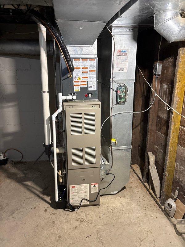 Completed full air conditioning system replacement including outdoor condensing unit and indoor air handler components. Removed existing equipment and installed new gray condensing unit on existing concrete pad with proper refrigerant line connections. Installed new indoor air handler in basement utility area adjacent to existing furnace and water heater. Ran new refrigerant lines with proper insulation, connected and secured all ductwork transitions using flexible and rigid metal ducting. Performed system startup procedures including refrigerant charge verification using manifold gauges, confirmed proper pressures on both high and low sides, tested electrical connections at disconnect box, and verified all safety controls. System tested and operating within manufacturer specifications with proper airflow and temperature differential across coil.