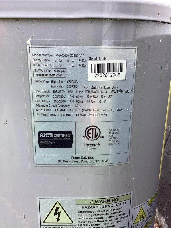 Responded to no cooling complaint on 2024 Trane model MAAC4030D1000AA heat pump system blowing room temperature air. Upon arrival, performed system diagnostics and visual inspection of outdoor unit and electrical connections. Documented existing conditions including weathered electrical service panel with visible corrosion on mounting hardware and terminals, and outdoor condensing unit showing normal exterior wear. System utilizes R410A refrigerant with rated charge of 5 lbs 12 oz, operating on 208/230V electrical service. Captured photographic documentation of equipment nameplate data, electrical connections, and overall unit condition for service records.