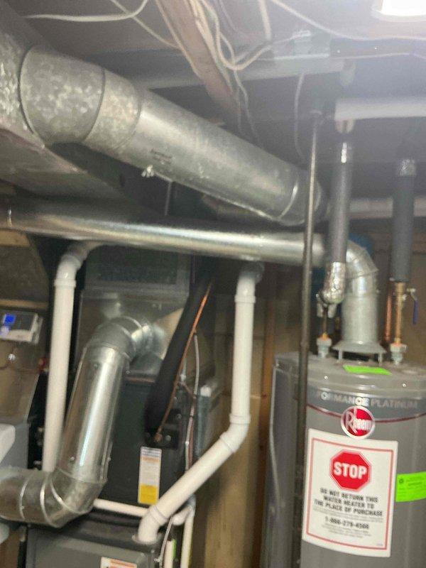 Responded to customer request for water heater replacement estimate. Evaluated existing Rheem water heater installation in basement utility area, documented equipment condition and surrounding mechanical infrastructure including HVAC system, ductwork, and associated plumbing connections. Photographed water heater unit showing standard safety labeling, copper supply piping with brass fittings, PVC drain lines, and clearance spacing relative to furnace equipment. No active service issues or symptoms reported at time of inspection. Provided replacement options and estimate for future water heater installation.