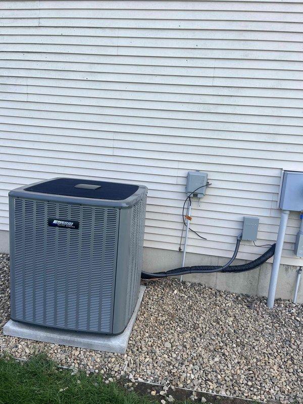 Completed full air conditioning system replacement at residential property. Installed new outdoor condenser unit on existing concrete pad with gravel surround, mounted unit against exterior wall with white vinyl siding. Ran new refrigerant lines with proper insulation along exterior wall, installed electrical disconnect box and junction boxes with conduit for power supply. System charged with refrigerant per manufacturer specifications: factory charge of 12 oz plus field charge of 4.5 oz for total system charge of 96.5 oz. Verified all electrical connections, tested system operation, and confirmed proper cooling performance. Installation completed as same-day service call with all work meeting code requirements and manufacturer guidelines.