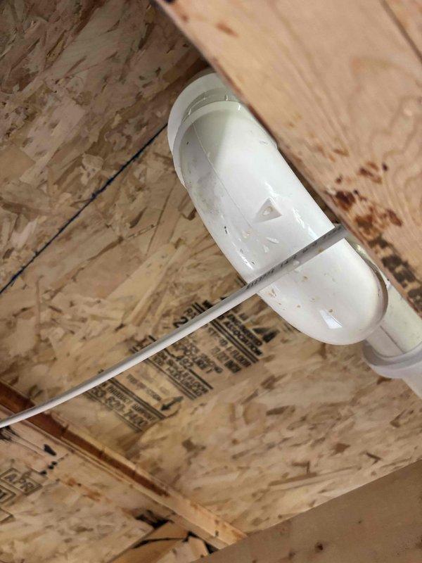 Responded to water leak complaint originating from HVAC distribution box in attic space. Inspected 18-year-old system and located active dripping from condensate drain line assembly. Found PVC drain piping with compromised seal at coupling joint, evidenced by moisture staining on adjacent wooden framing members. Documented pipe configuration and leak source with photographic evidence. System confirmed operational for both heating and cooling functions at time of inspection. Advised potential connection to previous water damage incident from April.