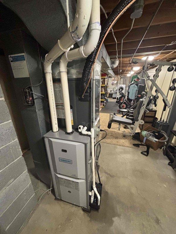 Completed full air conditioning system replacement in residential basement utility area. Removed existing AC unit and installed new ComfortMaker HVAC system with proper venting configuration using white PVC piping extending vertically from unit through ceiling joists. Connected black flexible ductwork to system for air distribution. Ensured all refrigerant lines, condensate drainage, and electrical connections were properly installed and secured. Verified system operation, airflow, and temperature output. Unit positioned on concrete floor against cinderblock wall with adequate clearance for service access. All installation work performed to manufacturer specifications and local code requirements. System tested and operational upon completion.
