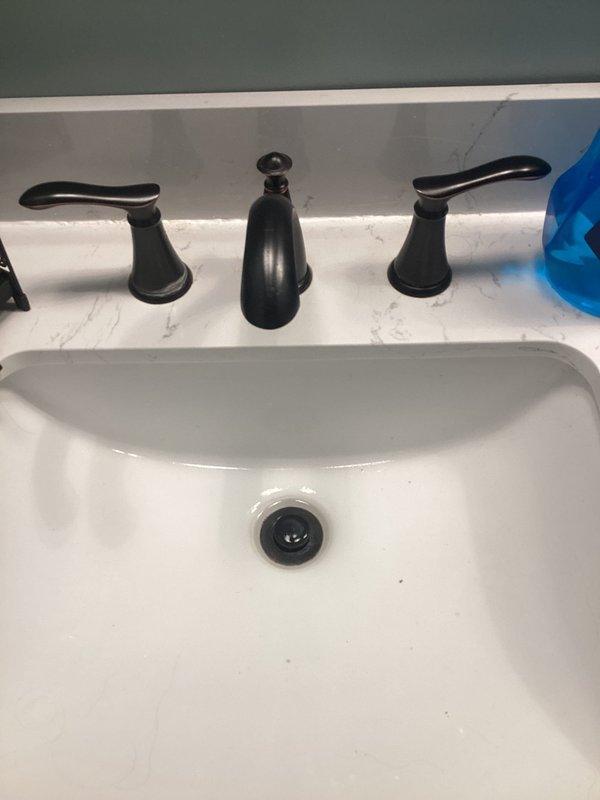 Responded to bathroom faucet leak and slow-draining sink in 161-year-old home. Inspected widespread three-handle faucet configuration with oil-rubbed bronze finish and undermount porcelain basin. Identified leak source at faucet connection points and addressed drainage issue affecting bathroom sink for approximately one month. Performed necessary repairs to restore proper function to both faucet and drain system, ensuring no water leakage and improved drainage flow. Verified repairs and confirmed issue was isolated to bathroom only with no other plumbing concerns throughout the home.