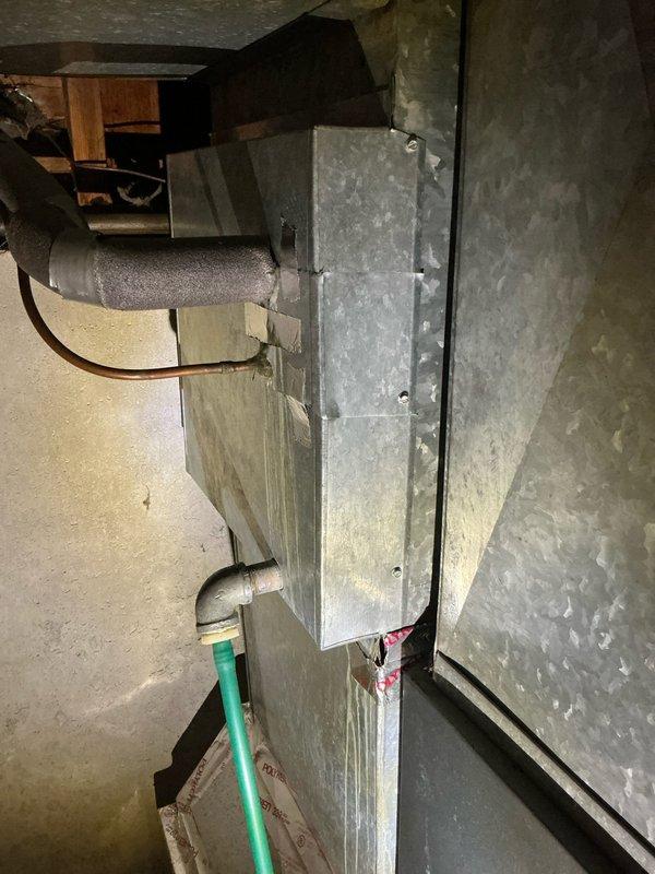 Performed sales estimate for aging HVAC system with suspected refrigerant leak. Inspected 30-year-old furnace and air handler unit in basement showing significant wear and corrosion on galvanized ductwork, along with 16-year-old outdoor condensing unit positioned on concrete block platform against exterior wall. Documented current system condition through photographs of interior air handler with deteriorated metal surfaces and exterior AC unit with weathered housing, assessed equipment for replacement recommendations due to age and suspected leak requiring repair versus full system replacement evaluation.