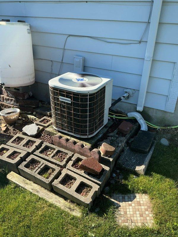 Performed sales estimate for aging HVAC system with suspected refrigerant leak. Inspected 30-year-old furnace and air handler unit in basement showing significant wear and corrosion on galvanized ductwork, along with 16-year-old outdoor condensing unit positioned on concrete block platform against exterior wall. Documented current system condition through photographs of interior air handler with deteriorated metal surfaces and exterior AC unit with weathered housing, assessed equipment for replacement recommendations due to age and suspected leak requiring repair versus full system replacement evaluation.
