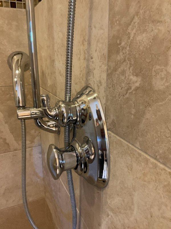 Completed return visit to address gap between shower handle escutcheon and wall following previous cartridge replacement on thermostatic shower control system. Adjusted chrome fixture assembly and escutcheon plate to eliminate spacing issue and ensure proper fit against tiled wall surface. No charge service call to finalize previous repair work.