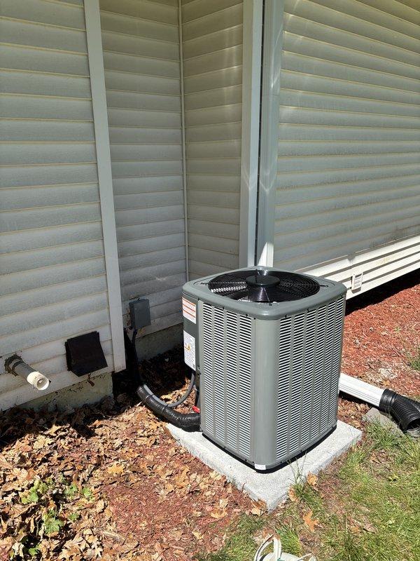 Completed full air conditioning system replacement including outdoor condensing unit and indoor air handler. Removed existing equipment and installed new cylindrical condensing unit with horizontal louvers on existing concrete pad adjacent to building exterior. Connected refrigerant lines, electrical disconnect, and condensate drainage. Installed new indoor air handler in basement utility area, integrated with existing furnace system. Completed all ductwork connections to existing plenum and distribution system. Verified proper refrigerant charge, tested electrical connections, and confirmed system operation. All equipment labeled with manufacturer specifications and operating within normal parameters.