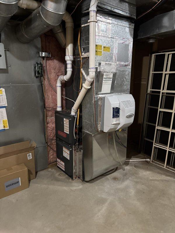 Completed full air conditioning system replacement including outdoor condensing unit and indoor air handler. Removed existing equipment and installed new cylindrical condensing unit with horizontal louvers on existing concrete pad adjacent to building exterior. Connected refrigerant lines, electrical disconnect, and condensate drainage. Installed new indoor air handler in basement utility area, integrated with existing furnace system. Completed all ductwork connections to existing plenum and distribution system. Verified proper refrigerant charge, tested electrical connections, and confirmed system operation. All equipment labeled with manufacturer specifications and operating within normal parameters.