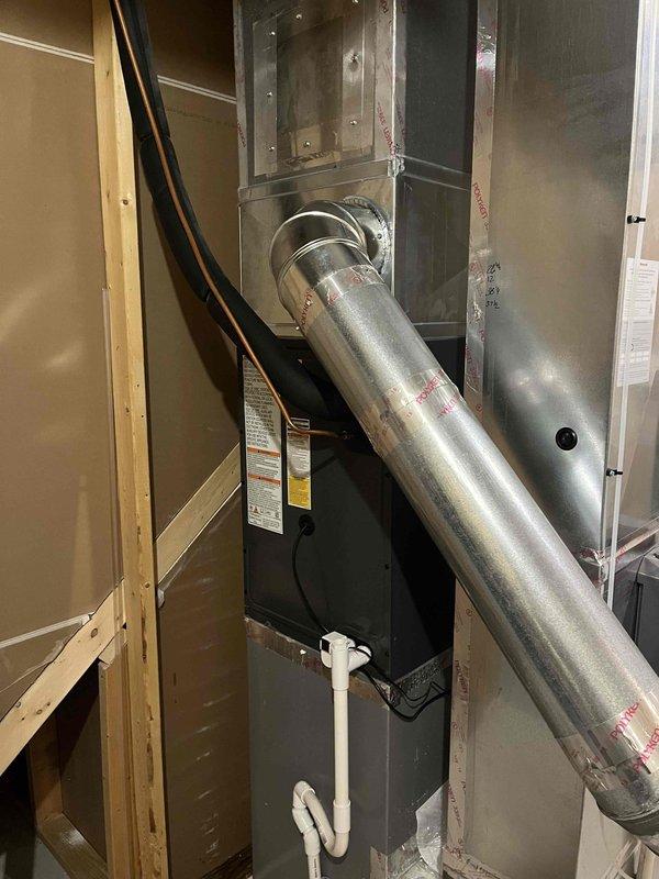 Completed full air conditioning system replacement including outdoor condenser unit and indoor air handler. Installed new gray condenser unit on existing concrete pad with proper clearances, connected refrigerant lines, and established electrical connections via exterior junction box. Mounted new air handler in mechanical room with supply plenum and ductwork connections, installed condensate drain line with PVC piping, and verified all electrical wiring and safety controls. System commissioned and tested for proper operation, refrigerant charge confirmed, and all components verified functional.