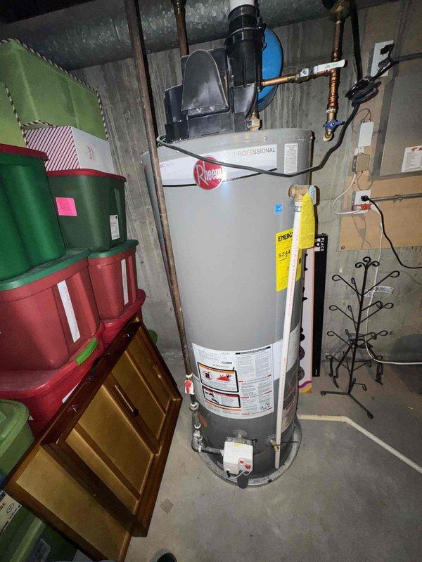 Returned to property to document existing HVAC equipment for estimate preparation. Photographed Rheem Professional water heater installation in basement utility area, including all connected plumbing components, copper piping, blue-handled valves, and black exhaust venting. Documented residential furnace system with white PVC venting pipes secured with mounting straps and metal ductwork connections. Captured detailed images of equipment labels, specifications, and current installation configuration to support accurate estimate development.