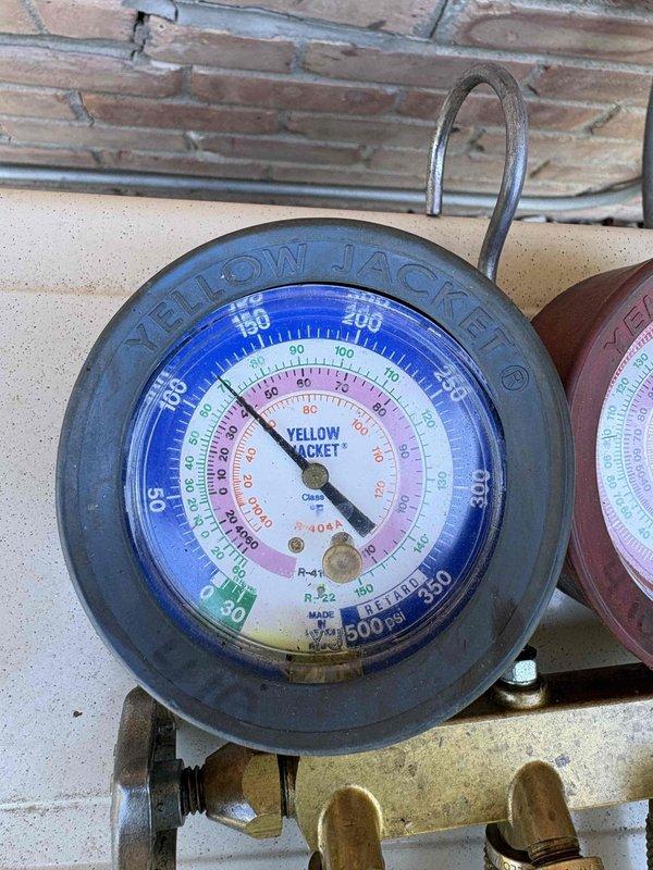 Responded to service call for 9-year-old mini-split system experiencing freeze-over conditions and water leakage. Unit was ejecting ice from front discharge, though condensate line had been previously cleared and was draining properly. Diagnosed low refrigerant charge as root cause of evaporator coil icing. Performed system evacuation using vacuum pump, then recharged system to manufacturer specifications using calibrated refrigerant scale. Verified proper operating pressures on gauge manifold and confirmed system returned to normal operation without ice formation.