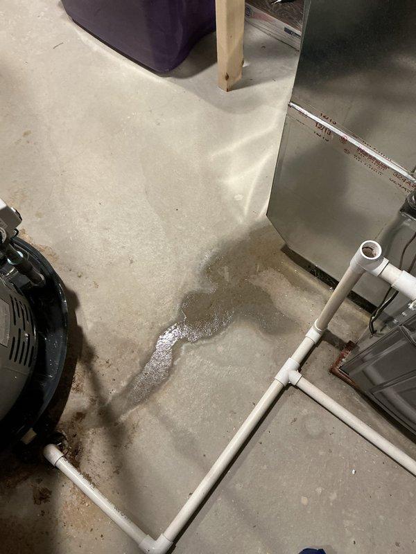 Responded to water leak complaint beneath furnace with unusual noises. Upon inspection, discovered active water accumulation on utility room floor originating from HVAC condensate drainage system. Identified rust staining and corrosion along drain pan seam on 11-year-old furnace unit, indicating compromised pan integrity. Documented water pooling with visible foam accumulation and mineral deposits in drain pan, confirming condensate drainage issue rather than furnace malfunction. PVC drainage piping appeared intact with no visible damage. System currently maintaining heating and cooling functionality despite drainage concern. Photographed affected areas including floor water accumulation and corroded drain pan for documentation purposes.