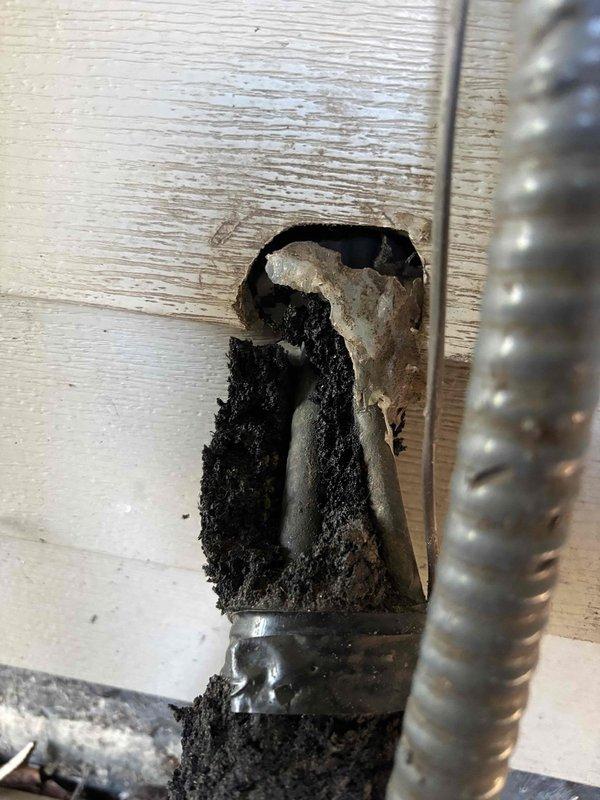 # CP-Cooling Problem Resolution

Responded to service call for 16-year-old air conditioning system running but not producing cold air. Upon arrival, performed visual inspection of outdoor condenser unit, which showed significant weathering, accumulated debris, and grime buildup on protective grille and coil surfaces. Documented existing condition with photographs.

During inspection, discovered evidence of previous electrical fire damage at wall penetration point where refrigerant lines and electrical conduit enter structure. Burn damage was extensive with charred wood framing and damaged insulation visible around opening. This fire damage likely compromised electrical connections and/or refrigerant line integrity, resulting in system malfunction and loss of cooling capacity.

Advised customer of fire damage findings and potential safety concerns. Recommended immediate electrical inspection and complete system evaluation to determine extent of damage to refrigerant lines, electrical wi