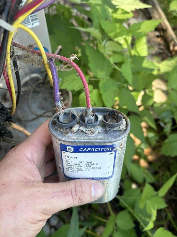 Responded to no heating or cooling complaint on 23-year-old Lennox system with 2-year-old thermostat. Upon inspection, discovered failed run capacitor on outdoor condensing unit preventing compressor operation. Capacitor exhibited severe corrosion, oxidation, and deteriorated wire connections with visible mineral deposits at terminals. Removed defective GE capacitor and replaced with new dual-run capacitor rated at 370 VAC. Cleaned terminal connections, secured all wiring, and verified proper voltage at contactor. Cycled system through heating and cooling modes to confirm proper operation. Thermostat now successfully communicating with HVAC equipment and system restored to full functionality.