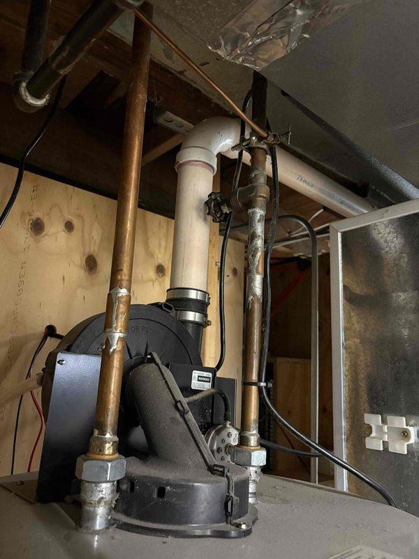 Conducted comprehensive assessment of existing water heater system and associated plumbing infrastructure in basement utility area. Documented current mechanical installation including pump assembly, copper and PVC piping configurations, and existing equipment conditions showing age-related wear and patina on copper lines. Photographed overhead plumbing systems, exposed joists, ductwork, and utility room layout to provide detailed estimate for water heater replacement.