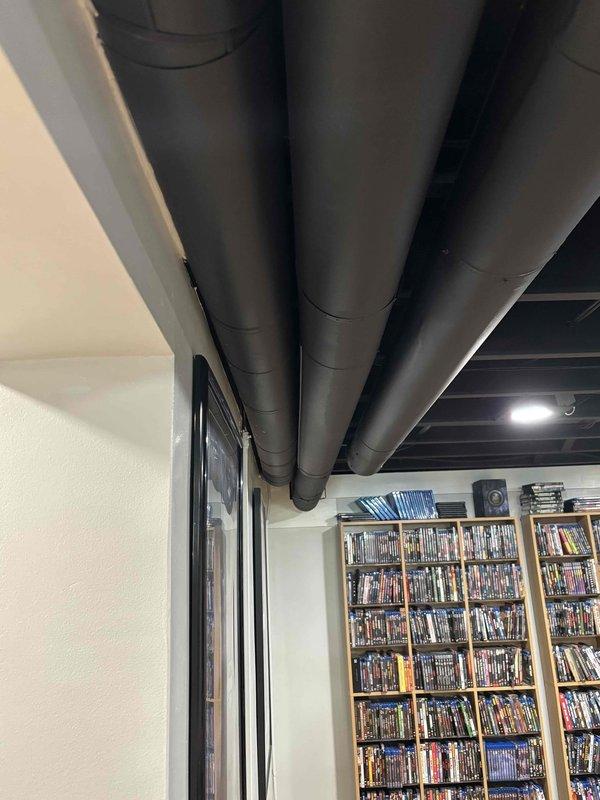 Responded to service call for lack of airflow from one vent in home. Performed system inspection and evaluated ductwork in basement area where customer reported airflow issues. Inspected exposed HVAC ductwork running through finished basement space with media storage. Examined duct runs, connections, and insulation for obstructions, disconnections, or damage that could restrict airflow to affected room. Assessed 29-year-old system condition and discussed equipment life expectancy with customer, confirming system is operating within normal parameters for its age. Documented ductwork configuration and routing with photos for service records.