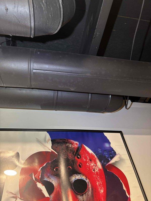 Responded to service call for lack of airflow from one vent in home. Performed system inspection and evaluated ductwork in basement area where customer reported airflow issues. Inspected exposed HVAC ductwork running through finished basement space with media storage. Examined duct runs, connections, and insulation for obstructions, disconnections, or damage that could restrict airflow to affected room. Assessed 29-year-old system condition and discussed equipment life expectancy with customer, confirming system is operating within normal parameters for its age. Documented ductwork configuration and routing with photos for service records.