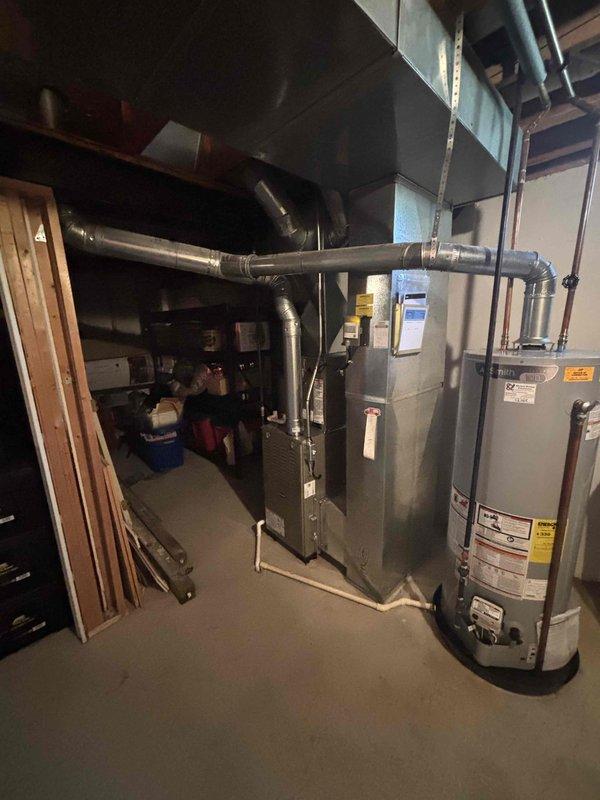 Completed full HVAC system installation including new furnace and air conditioning condenser unit. Furnace installed in basement utility area with proper ductwork connections and venting configured. AC condenser unit positioned on concrete pad in exterior location with electrical conduit properly routed along building exterior. All refrigerant lines connected between indoor and outdoor components. System tested for proper operation, airflow verified, and installation documented with photographs showing completed equipment placement and final configuration.
