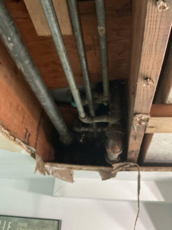 Responded to reported leak in toilet supply line. Upon inspection, accessed ceiling cavity and basement utility area to trace plumbing lines. Evaluated existing PVC drainage system, copper supply lines, and associated connections throughout the affected zones. Identified and assessed condition of pipes running through ceiling joists and vertical supply runs. Completed diagnostic inspection of plumbing infrastructure including shut-off valves and pipe joints in mechanical room area. Documented findings with photographic evidence showing accessible plumbing components and structural routing of water supply and drainage systems.