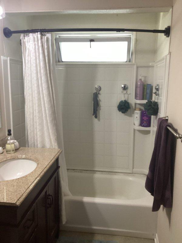 Conducted on-site assessment for bathroom renovation project. Documented existing conditions of full bathroom including toilet, vanity with granite countertop and undermount sink, tub/shower combination with tile surround, built-in corner shelving, window above tub, and all plumbing fixtures. Photographed current layout and fixtures to prepare comprehensive plumbing project estimate for complete bathroom remodel.