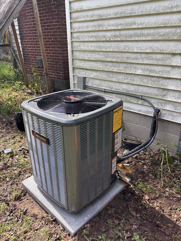 Completed full air conditioning system replacement at residential property. Removed existing AC condensing unit and installed new outdoor condensing unit on concrete pad with proper clearance between structures. Refrigerant lines were installed and insulated, routed along exterior wall through vinyl siding penetration. Indoor air handler was installed in basement utility area with proper integration to existing furnace system. White PVC condensate drainage and venting piping was installed per manufacturer specifications. All electrical connections completed, system charged with refrigerant, and unit tested for proper operation. System startup confirmed satisfactory airflow, temperature differential, and overall performance within manufacturer parameters.