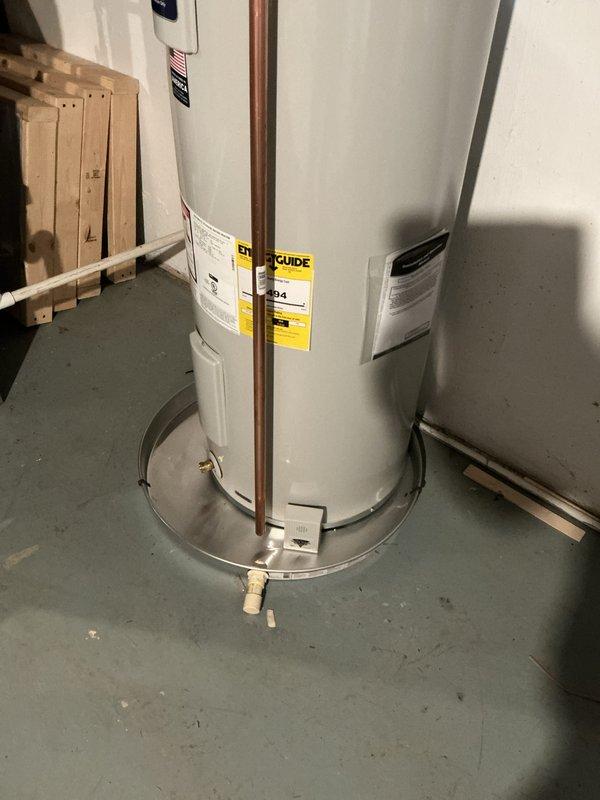 Completed installation of a 50-gallon tall electric water heater with expansion tank in basement utility area. Installed unit on metal drip pan with proper copper piping connections, brass fittings, and flexible supply lines to meet code requirements. All plumbing connections secured and tested for proper operation.