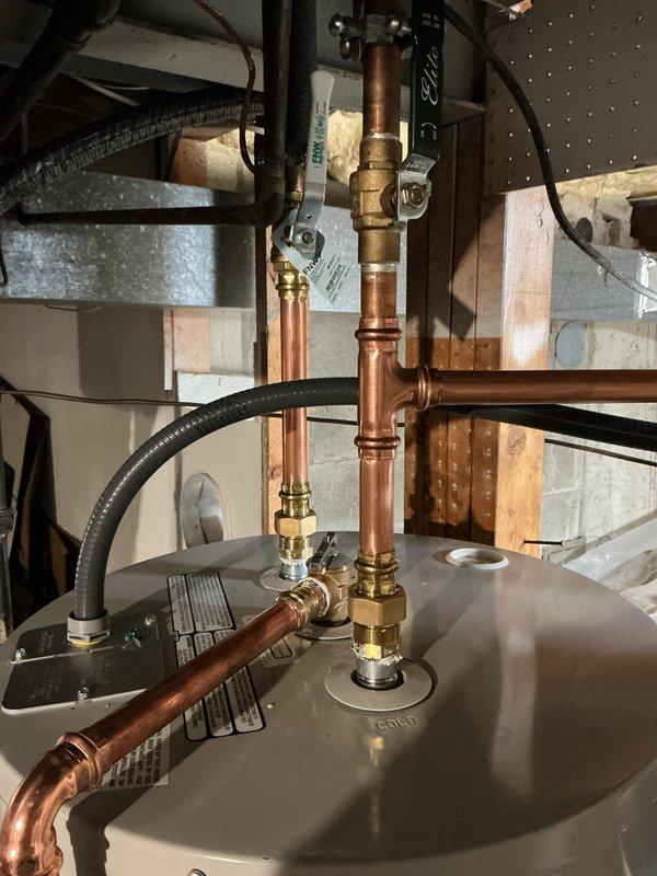 Completed installation of a 50-gallon tall electric water heater with expansion tank in basement utility area. Installed unit on metal drip pan with proper copper piping connections, brass fittings, and flexible supply lines to meet code requirements. All plumbing connections secured and tested for proper operation.