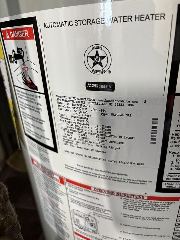 Completed installation of a 50-gallon Bradford White power vent natural gas water heater in utility room. Unit was properly connected with copper piping, brass fittings, and power vent exhaust system, with all manufacturer specifications and safety clearances met per code requirements.