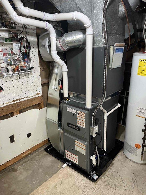 Completed full furnace installation in residential basement utility room. Installed new high-efficiency furnace unit with proper venting system utilizing white PVC condensate drainage piping with appropriate elbows and connections. Mounted metallic transition piece and plenum connector at furnace top. Ran electrical conduit and made all necessary power connections to unit. Installed corresponding air handler unit in attic space with reflective foil-faced insulation on rectangular plenum box. Connected flexible aluminum ductwork from air handler to existing distribution system, ensuring proper routing and support. Installed white PVC condensate drain line for attic unit. Verified all manufacturer specifications, tested system operation, and confirmed proper airflow throughout. All equipment labeled and secured according to code requirements.