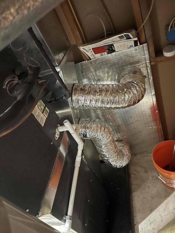Completed full furnace installation in residential basement utility room. Installed new high-efficiency furnace unit with proper venting system utilizing white PVC condensate drainage piping with appropriate elbows and connections. Mounted metallic transition piece and plenum connector at furnace top. Ran electrical conduit and made all necessary power connections to unit. Installed corresponding air handler unit in attic space with reflective foil-faced insulation on rectangular plenum box. Connected flexible aluminum ductwork from air handler to existing distribution system, ensuring proper routing and support. Installed white PVC condensate drain line for attic unit. Verified all manufacturer specifications, tested system operation, and confirmed proper airflow throughout. All equipment labeled and secured according to code requirements.