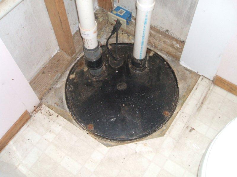 Responded to sewage lift pump issue where existing sump pump required replacement due to sump basin being positioned lower than the drain field elevation. Assessed plumbing assembly in confined utility space with multiple white PVC discharge lines and existing black pump unit with blue control sensor. Replaced failed sump pump system to restore proper sewage lifting capability and ensure adequate discharge pressure to overcome elevation differential to drain field.