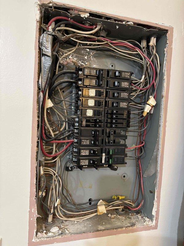 Completed comprehensive electrical club inspection of residential service equipment and outdoor HVAC electrical installations. Documented existing conditions of main electrical panel showing older-style wiring with multiple circuits, noted accumulated debris and age-related deterioration within panel enclosure. Inspected exterior electrical components including meter housings, service conduit, and disconnect equipment serving two air conditioning units. Photographed weathered metal conduit showing oxidation and overall electrical infrastructure condition for compliance documentation and future reference.