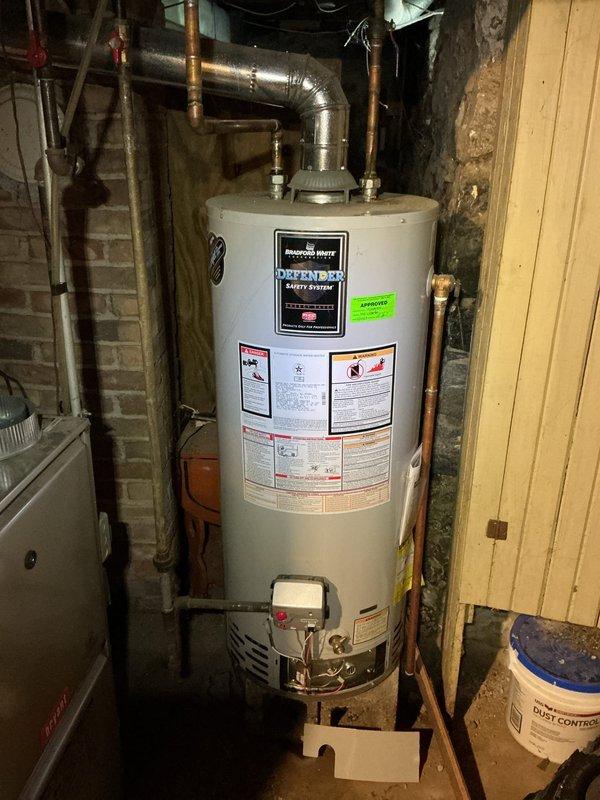 Responded to service call for non-functioning water heater with water present in drain pan. Upon inspection, found 10-year-old Bradford White water heater in basement utility area showing signs of failure. Discovered significant internal corrosion and deterioration of tank components, with rust-colored oxidation and moisture damage throughout the system. Observed accumulated debris and insulation fragments inside compromised components, indicating advanced deterioration and structural failure. Water heater had reached end of service life with tank integrity compromised, causing water leakage into catch pan. Documented conditions with photographs showing extent of corrosion and component failure for replacement recommendation.