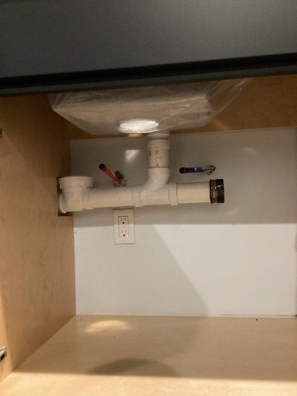 Installed drop-in sink in basement bar area with complete plumbing assembly including hot and cold water supply lines with shut-off valves and drain configuration. Mounted faucet fixture to sink and connected all water supply connections, ensuring proper function and no leaks upon testing.