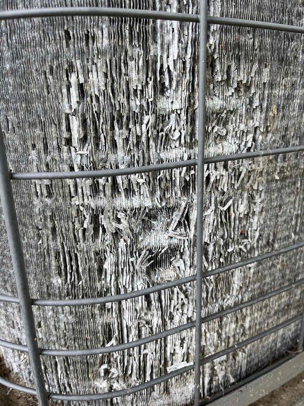 Completed annual cooling maintenance on 22-year-old Heil air conditioning system. Performed comprehensive tune-up inspection of outdoor condenser unit and indoor components. Found evaporator coil heavily contaminated with thick accumulation of dust, dirt, and debris causing significantly restricted airflow. Coil surface showed extensive buildup with matted and compressed fibrous material throughout the wire cage structure, indicating prolonged operation without proper maintenance. Outdoor condenser unit showed moderate soiling of fins and typical weathering from environmental exposure. Documented equipment condition with photographs for customer records. System operational at time of service visit.